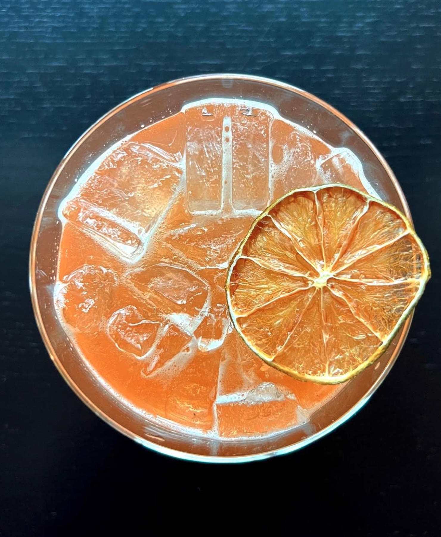 A cocktail garnished with a dried orange slice