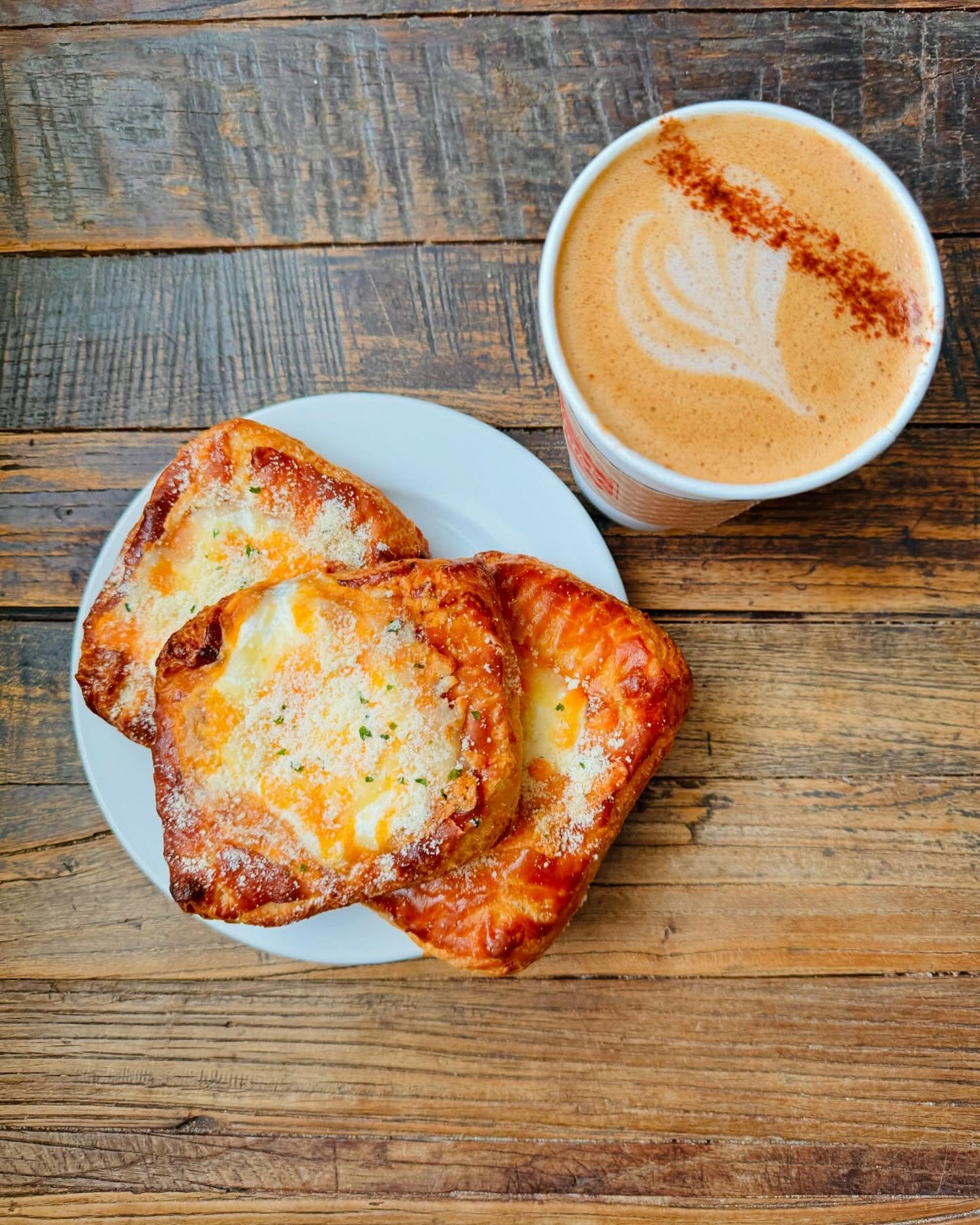 A pastry and a latte on a wooden table
